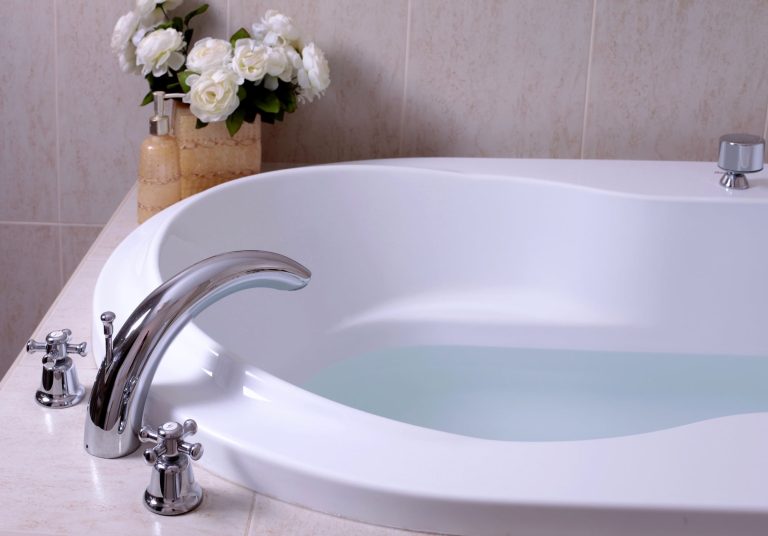 White bathtub with a chrome faucet, a common standard bathtub size for an alcove