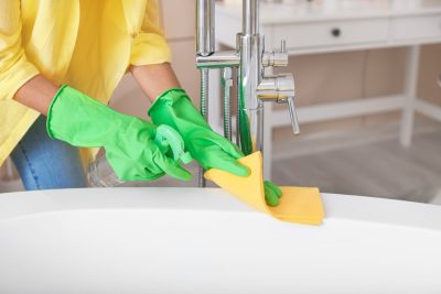 Beautiful young woman cleaning bathroom